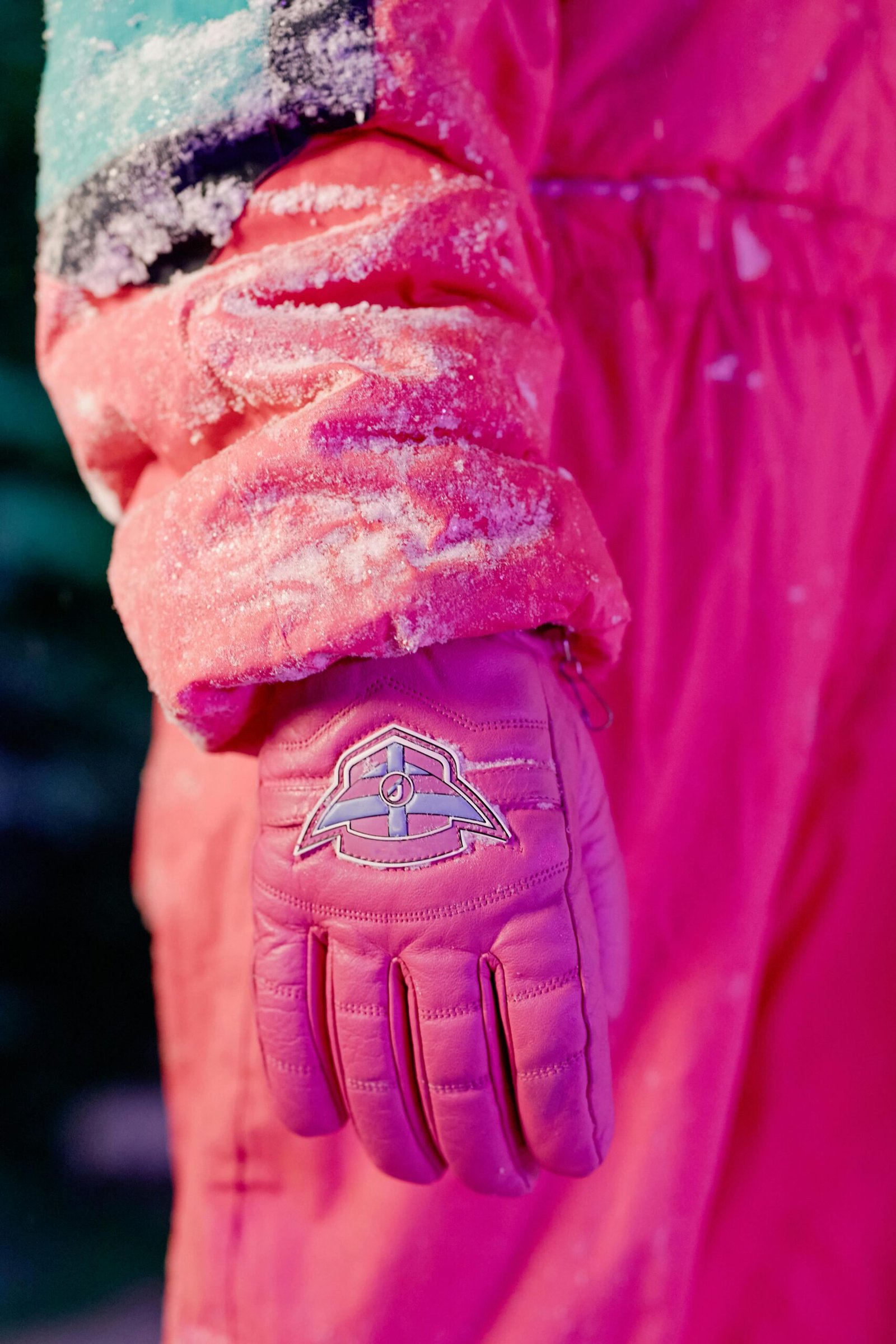 Vibrant close-up of a snow-covered glove and jacket with unique color contrast.